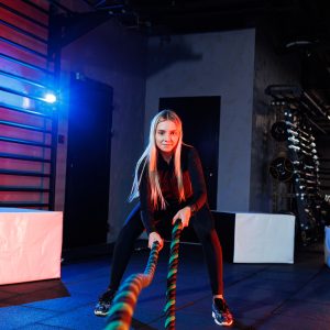 a sportive woman does exercises using sports equipment rope, goes in for sports in the gym.